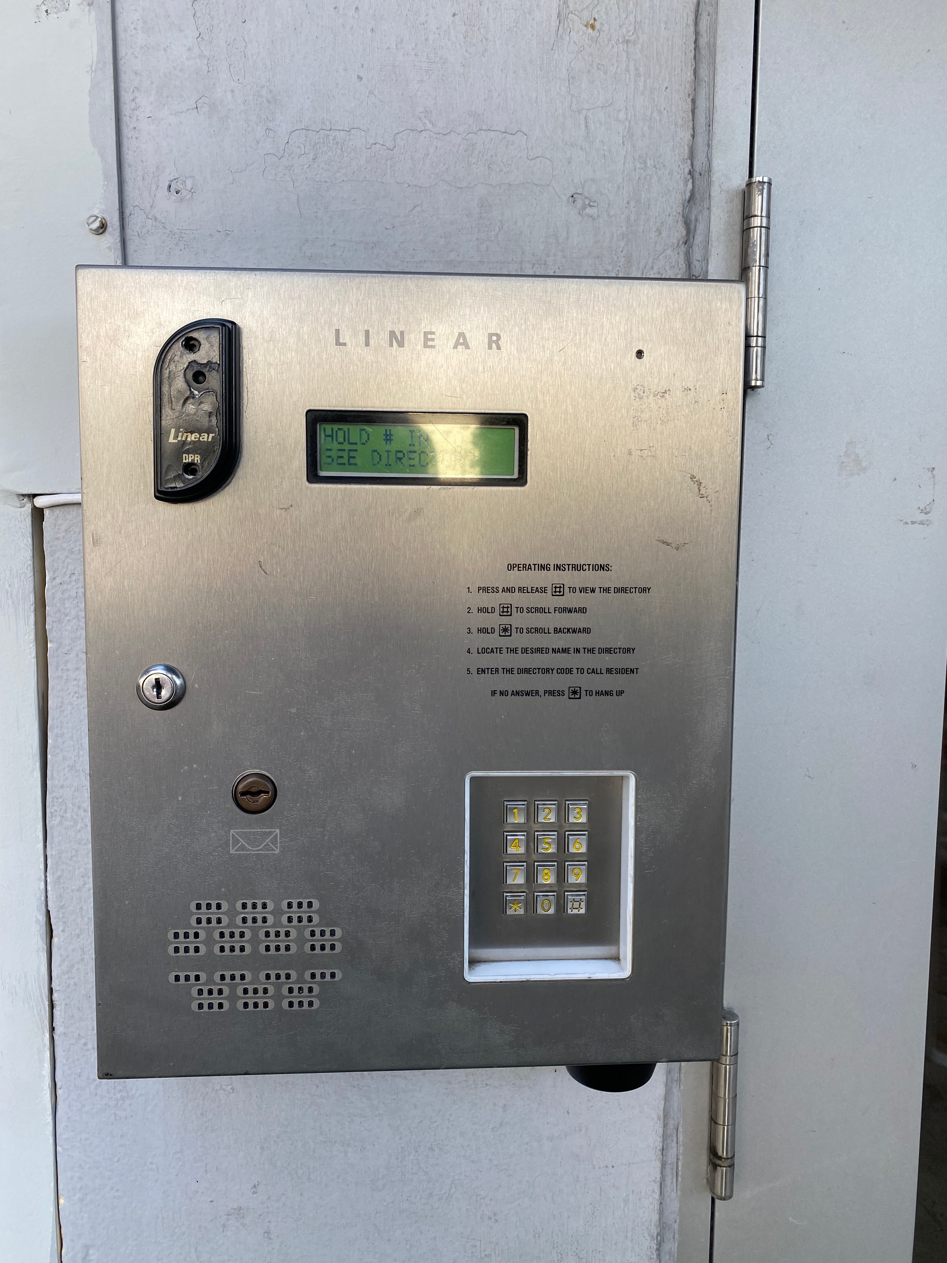 Picture of the keybad at our front door. It has a black receiver on the top left, a small screen just to the right of that, and a keypad on the bottom right. The whole keypad is made out of some stainless-steel looking metal.